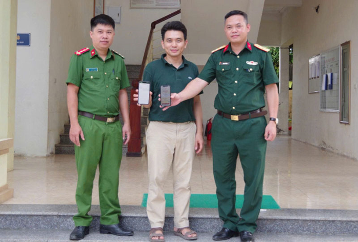 Trung tá Đinh Văn Tuấn (bên phải) chuyển lại số tiền cho anh Lê Trọng Nghĩa.Ảnh: MINH VƯƠNG