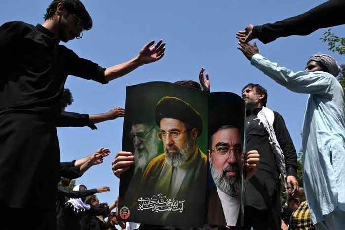 Một người Hồi giáo Shia cầm tấm áp phích có chân dung Lãnh tụ tối cao Iran Mojtaba Khamenei và cố Lãnh tụ tối cao Ayatollah Ali Khamenei (bên trái). Ảnh: Getty