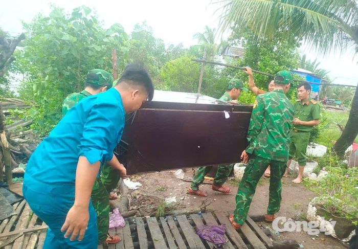 Cán bộ, chiến sĩ Đồn Biên phòng Đất Mũi giúp người dân di dời các dụng cụ trong nhà.