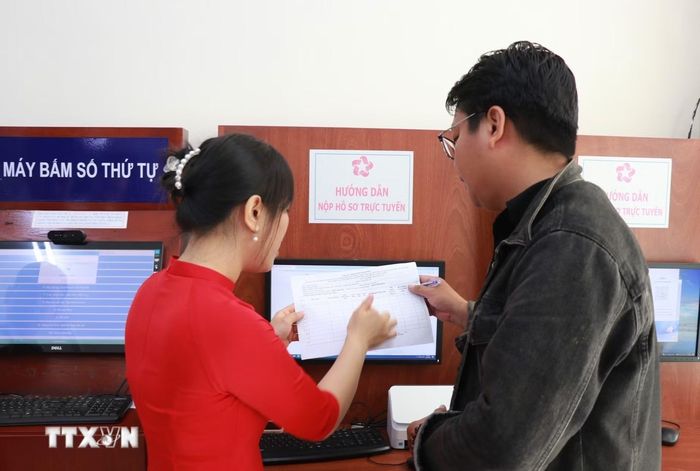 Cán bộ phường hướng dẫn người dân nộp hồ sơ trực tuyến. (Ảnh: Phan Sáu/TTXVN)