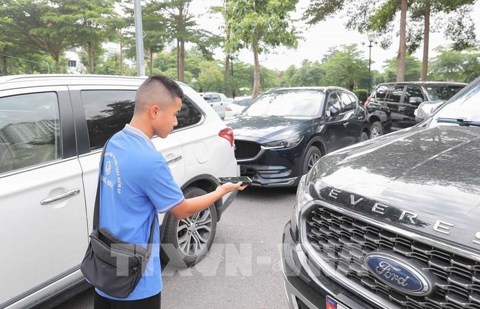 Nhân viên bãi trông giữ xe của Công ty TNHH Thương mại và Dịch vụ Đầu tư Khai thác Điểm đỗ Long Biên thực hiện thanh toán không dùng tiền mặt cho mọi phương tiện vào bãi hằng ngày. Ảnh: Phan Phương – TTXVN