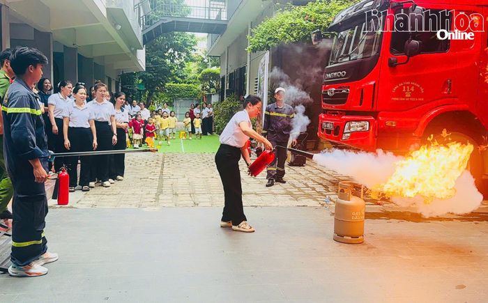 Giáo viên nhà trường thực hành sử dụng bình chữa cháy xách tay để dập lửa.
