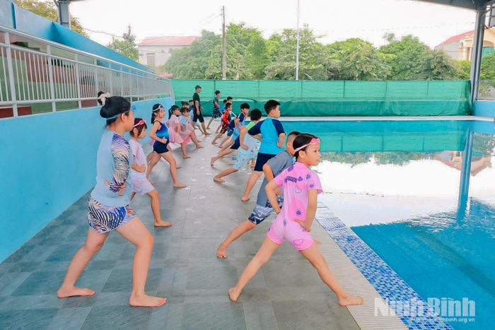 Huấn luyện viên hướng dẫn em học sinh tại xã Nho Quan các kỹ năng làm quen với nước trước khi thực hành những động tác bơi cơ bản.