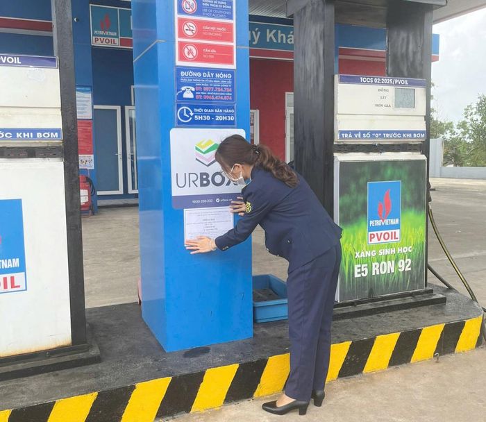 Lực lượng Quản lý thị trường Đà Nẵng thực hiện dán thông báo đường dây nóng tại các cửa hàng xăng dầu