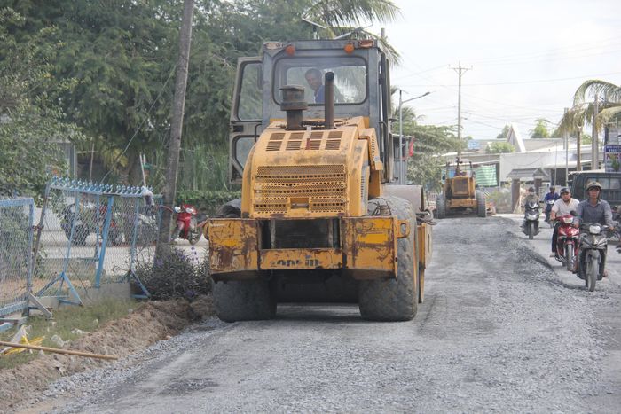 Xe cơ giới đang trải đá lu lèn để mặt đừng êm thuận đoạn gần cầu Đúc, trên QL30.
