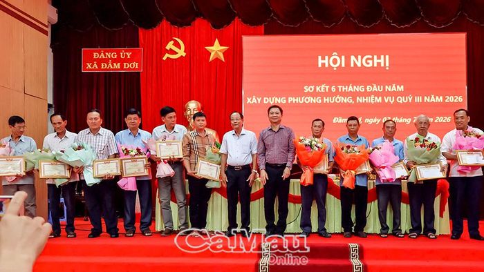 Đồng chí Nguyễn Bình Tân, Ủy viên Ban Thường vụ Tỉnh ủy, Phó Trưởng đoàn chuyên trách Đoàn đại biểu Quốc hội tỉnh ( bên phải) và đồng chí Huỳnh Văn Hiền, Bí thư Đảng ủy, Chủ tịch HĐND xã Đầm Dơi, trao giấy khen và tặng hoa tri ân các đồng chí nguyên Bí thư Chi bộ ấp nghỉ công tác do thực hiện sắp xếp ấp.