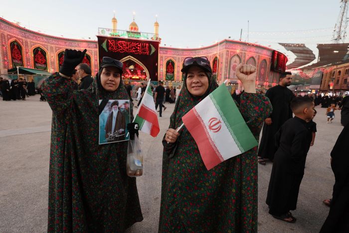 Một người hành hương Iran cầm bức ảnh của cố Lãnh tụ tối cao Iran Ali Khamenei và lá cờ Iran gần đền thờ Imam Hussein và Imam Abbas ở thành phố thánh Karbala (Iraq) ngày 3/7. Ảnh: Reuters.