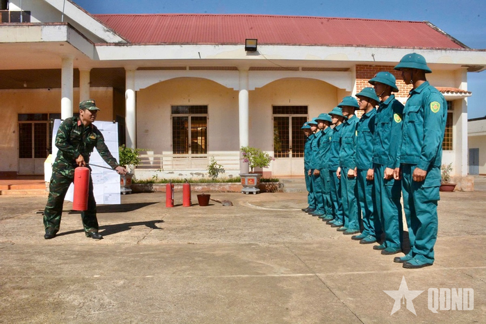 Cán bộ Ban CHQS xã Ea M'droh hướng dẫn lực lượng dân quân sử dụng bình cứu hỏa.