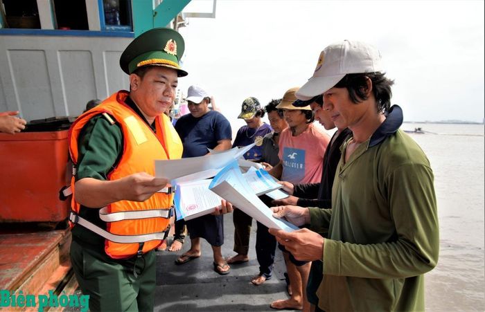 Cán bộ Đồn Biên phòng Tây Yên, Bộ đội Biên phòng tỉnh An Giang phát tờ rơi, tuyên truyền chống khai thác hải sản bất hợp pháp, không báo cáo và không theo quy định (IUU) cho ngư dân. Ảnh: Tuấn Kiệt