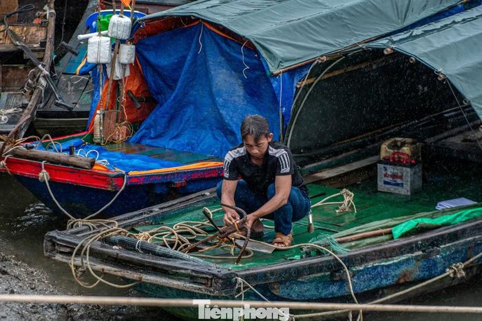 Một ngư dân đang cố gắng buộc lại dây neo để buộc nối các tàu với nhau tránh va đập.