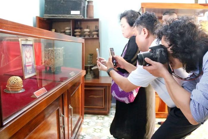 Du khách chụp ảnh bộ vương miện của Vua Pô Klong Mơh Nai và búi tóc của Hoàng hậu Po Bia Som bằng chất liệu vàng với đường nét chạm khắc hoa văn tinh xảo, độc đáo đầu thế kỷ XVII. (Ảnh: Nguyễn Thanh/TTXVN)