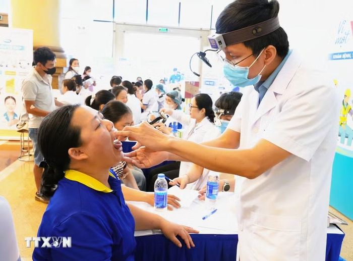 Bác sĩ khám tai mũi họng cho công nhân lao động. (Ảnh: Đồng Thúy/TTXVN)