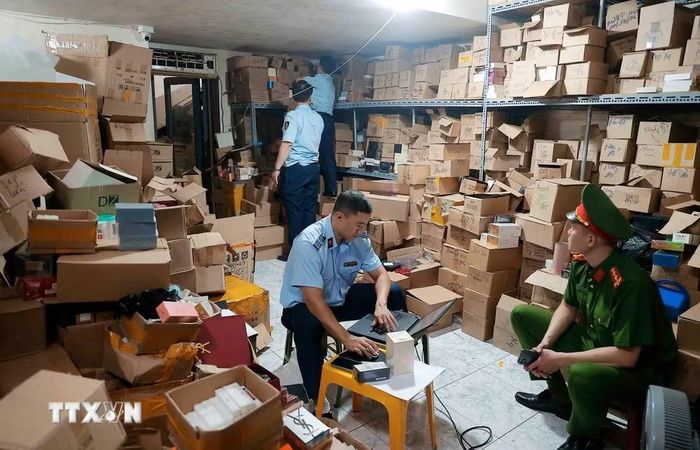 Lực lượng chức năng kiểm tra, thống kê số lượng tại một kho hàng phát hiện số lượng lớn nước hoa giả. (Ảnh: Trần Việt/TTXVN)