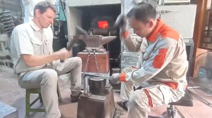 Du khách nước ngoài thích thú trải nghiệm làm dao tại xưởng rèn của nghệ nhân Lê Ngọc Lâm.