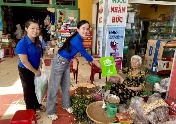 Đoàn viên, thanh niên xã Việt An tặng túi sử dụng nhiều lần cho tiểu thương tại chợ Việt An. Ảnh: NGUYỄN KIM