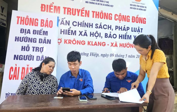 Thành viên Tổ công nghệ số cộng đồng xã Hướng Hiệp hướng dẫn người dân kích hoạt tài khoản định danh mức độ 2 - Ảnh: T.P