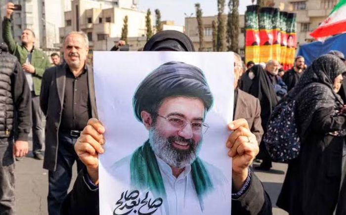Bên ngoài khu vực tổ chức tang lễ, nhiều người mang theo ảnh ông Mojtaba Khamenei - người được bầu kế nhiệm cha từ đầu tháng 3 nhưng đến nay vẫn chưa xuất hiện trước công chúng. Một số người cũng giương cao cờ vàng của lực lượng Hezbollah do Iran hậu thuẫn.