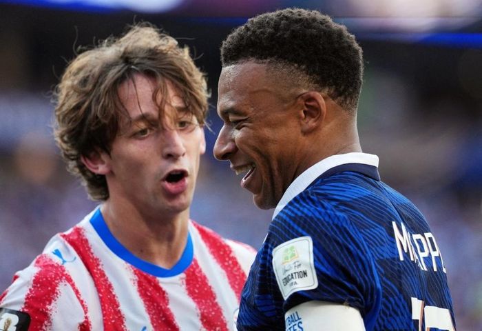 Mbappe cười đáp trả khi bị cầu thủ Paraguay khiêu khích. Ảnh: Reuters.