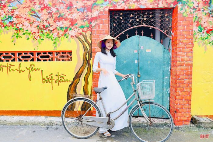 Trong tà áo dài truyền thống, nhiều bạn trẻ lựa chọn lưu lại những khoảnh khắc bên các bức bích họa rực rỡ sắc màu. Sự kết hợp giữa vẻ đẹp dịu dàng của tà áo dài với không gian nghệ thuật mang đậm hơi thở làng biển tạo nên những khung hình vừa hiện đại, vừa đậm bản sắc quê hương.