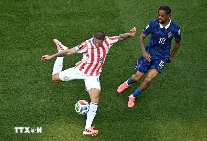 Hậu vệ Juan Jose Caceres (số 4) của Paraguay dứt điểm trước sự đeo bám của cầu thủ Pháp. (Ảnh: AFP/TTXVN)