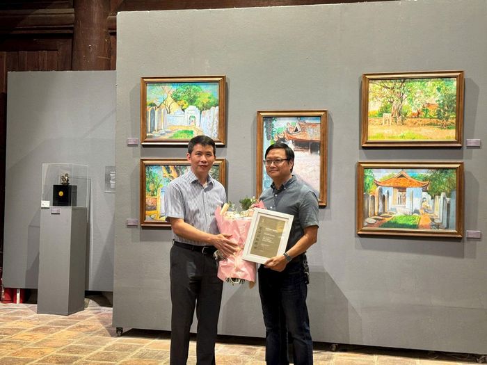 Giám đốc Sở Văn hóa và Thể thao Hà Nội Phạm Tuấn Long tặng hoa và chứng nhận cho giám tuyển Nguyễn Thế Sơn. Ảnh: Hoàng Lân