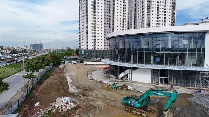 Chủ đầu tư dự án là Công ty CP Bến xe Thanh Trì, đơn vị được UBND TP Hà Nội cho thuê hơn 27.500m² đất tại khu vực Yên Sở từ đầu năm 2025 để triển khai. Thời điểm ghi nhận, máy xúc, xe nâng vẫn hoạt động sát chân tòa nhà đã lắp gần trọn mặt kính.