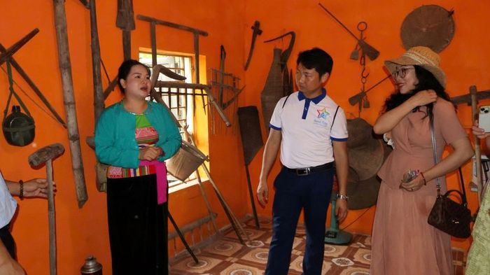 Chị Yến đứng trong không gian trưng bày hiện vật, giới thiệu nông cụ cho khách tham quan