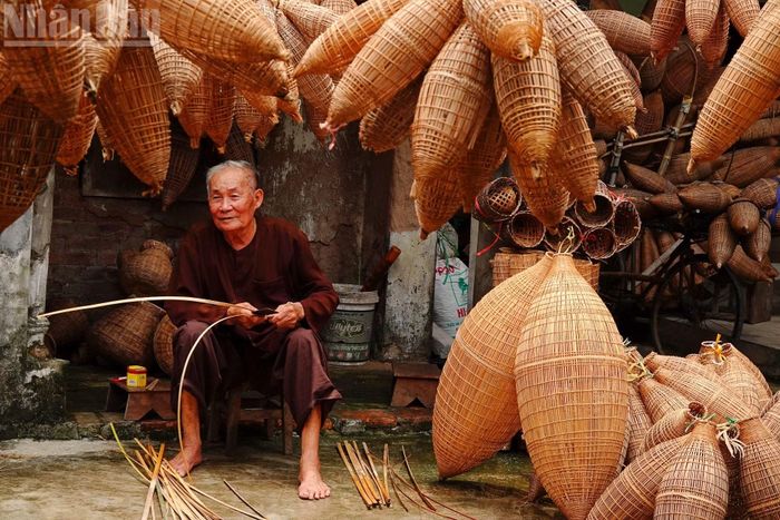 Ông Bạc ngồi tước những thanh tre bên hiên nhà. Ảnh: LINH VŨ