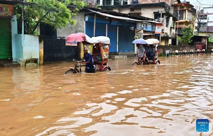 Người dân di chuyển qua vùng nước lũ sau đợt mưa lớn vào năm ngoái thành phố Guwahati, bang Assam, đông bắc Ấn Độ. (Ảnh: THX)