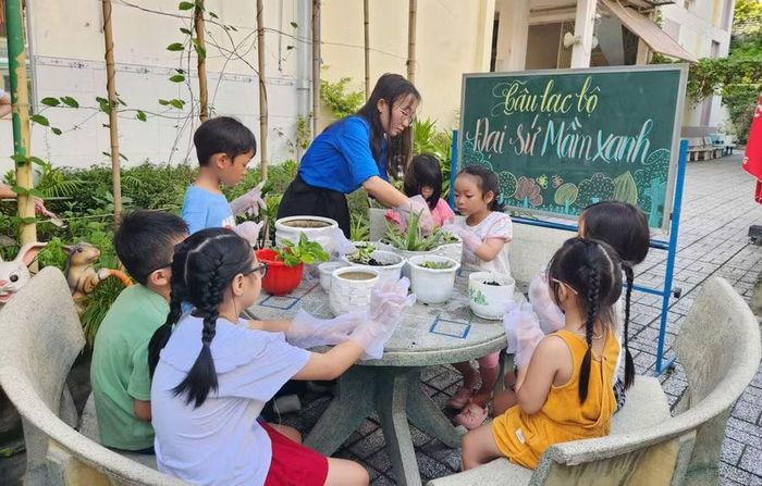 Giáo viên Trường Tiểu học Đinh Tiên Hoàng hướng dẫn các em nhỏ pha trộn đất, trồng những cây nhỏ vào chậu.