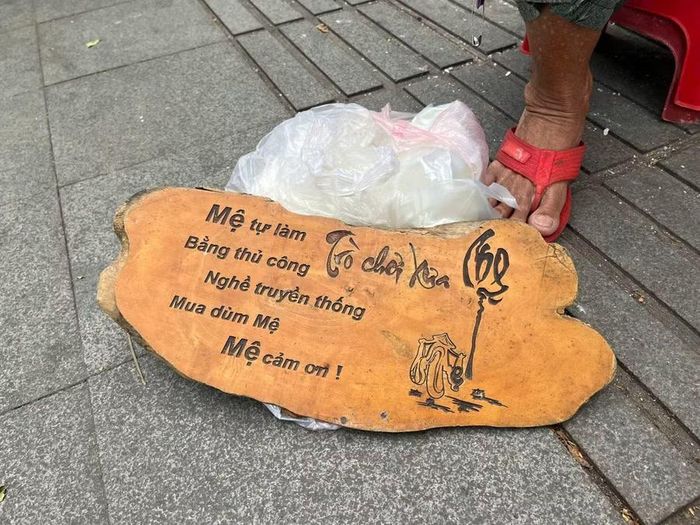 Bảng hiệu "cửa hàng" của mệ Hường được đặt dưới nền đất vỉa hè.