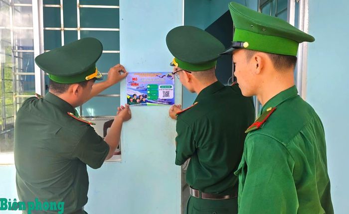 Cán bộ, chiến sĩ Đồn Biên phòng Rạch Gốc dán tờ rơi in nội dung thông tin về mô hình và mã QR Code tại trạm kiểm soát Biên phòng để ngư dân dễ dàng truy cập và gửi tin tố giác tội phạm khi ra khơi đánh bắt hải sản. Ảnh: Hoàng Tá