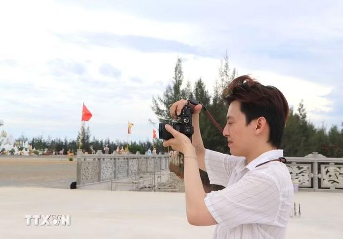 Một bạn trẻ sử dụng máy ảnh để ghi lại cảnh đẹp, làm video đưa lên các nền tảng xã hội. (Ảnh: Đinh Hương/TTXVN)