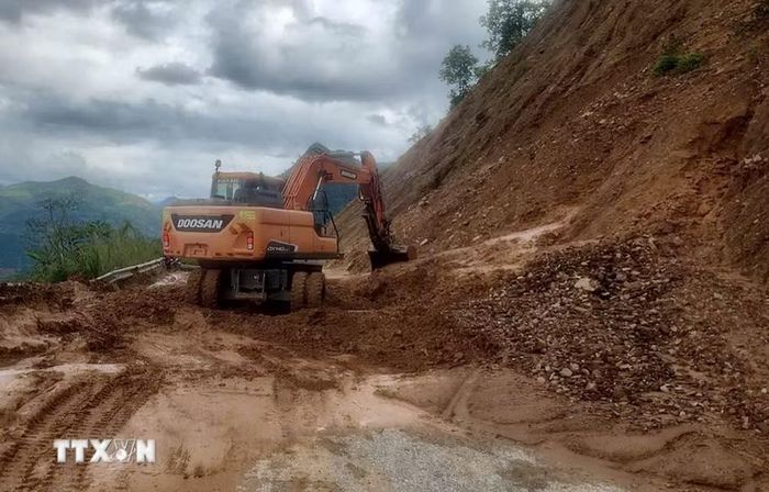 Đơn vị thi công huy động máy xúc khắc phục điểm sạt lở taluy dương tại Km22+200 thuộc Tỉnh lộ 144. (Ảnh: TTXVN phát)