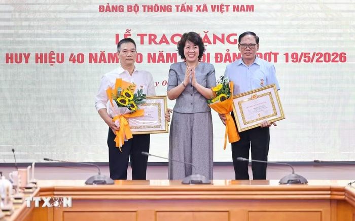 Đồng chí Nguyễn Thị Hoàng Vân, Phó Bí thư Đảng ủy, Trưởng Ban Tuyên giáo và Dân vận Đảng ủy các cơ quan Đảng Trung ương trao tặng Huy hiệu 30 năm, 40 năm tuổi Đảng cho đồng chí Phạm Huy Minh, Đảng bộ Ban Biên tập Ảnh và đồng chí Nguyễn Văn Bằng, Chi bộ Trung tâm Hợp tác quốc tế thông tấn. (Ảnh: Minh Đức/TTXVN)