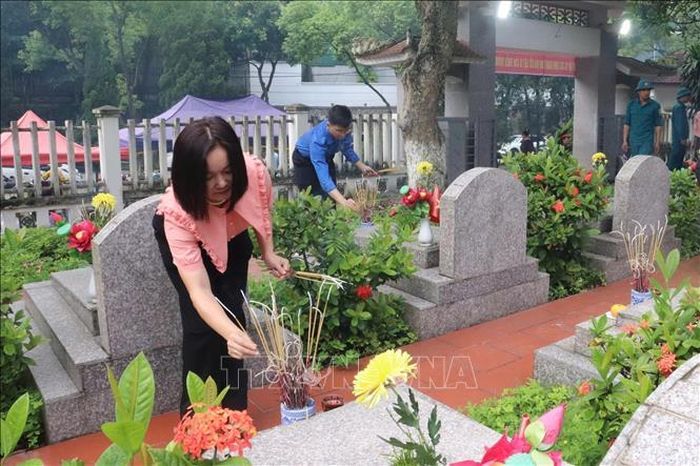 Thắp hương tại các phần mộ liệt sỹ. Ảnh: Hương Thu/TTXVN