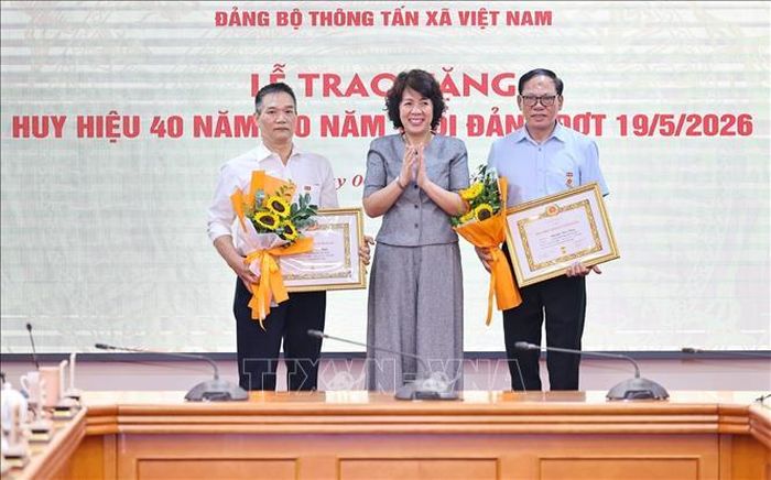 Đồng chí Nguyễn Thị Hoàng Vân, Phó Bí thư Đảng ủy, Trưởng Ban Tuyên giáo và Dân vận Đảng ủy các cơ quan Đảng Trung ương, trao tặng Huy hiệu 30 năm, 40 năm tuổi Đảng cho đồng chí Phạm Huy Minh, Đảng bộ Ban Biên tập Ảnh và đồng chí Nguyễn Văn Bằng, Chi bộ Trung tâm Hợp tác quốc tế thông tấn. Ảnh: Minh Đức/TTXVN