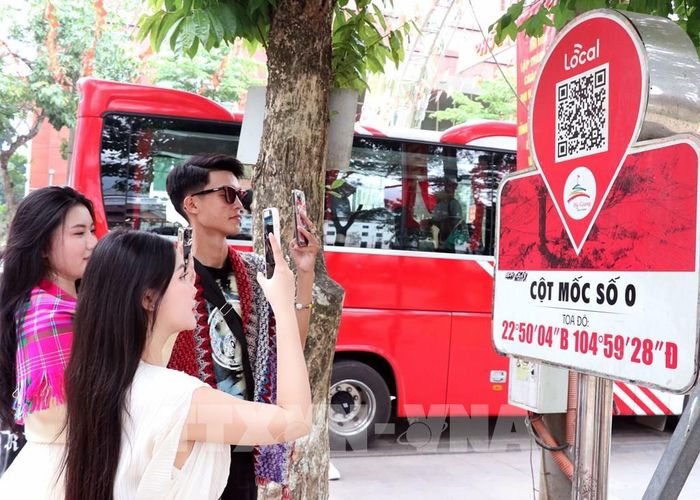 Du khách quét QR tại Km0 Hà Giang tim hiểu thông tin du lịch. Ảnh: Đức Thọ - TTXVN 