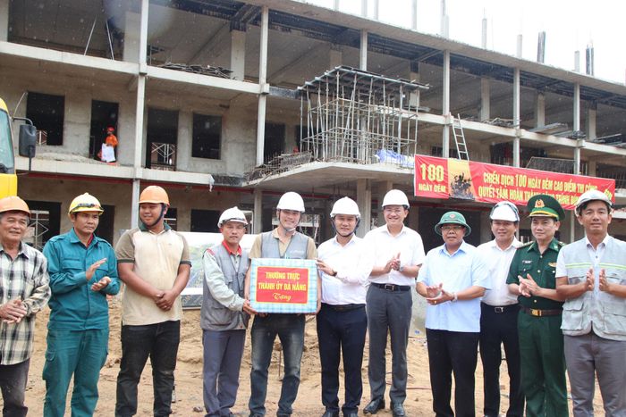 Phó Bí thư Thường trực Thành ủy Nguyễn Đình Vĩnh (thứ 6, từ phải qua) tặng quà, động viên đơn vị thi công dự án Trường phổ thông nội trú liên cấp tiểu học - trung học cơ sở Tây Giang. Ảnh: TRỌNG HUY