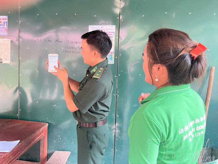 Cán bộ bộ đội biên phòng hướng dẫn người dân thao tác trên điện thoại thông minh.