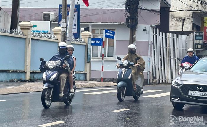 Người dân di chuyển trên đường Phan Trung trong cơn mưa chiều 6-7. Ảnh minh họa: Kim Liễu 