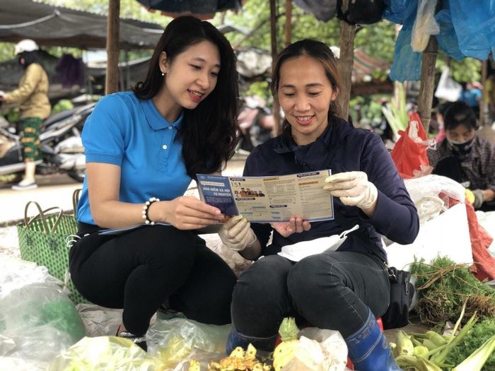 Cán bộ bảo hiểm xã hội tuyên truyền chính sách bảo hiểm xã hội tới tiểu thương. Ảnh: BHXHVN