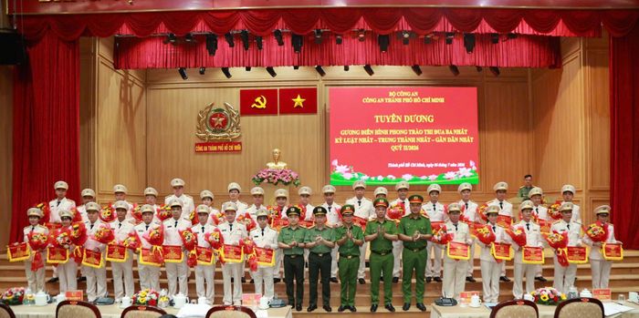 Đại tá Bùi Thanh Trực, Phó Giám đốc CATP trao Cờ tuyên dương và hoa cho các tập thể, cá nhân xuất sắc trong thực hiện phong trào thi đua “Ba nhất” trong Quý II/2026