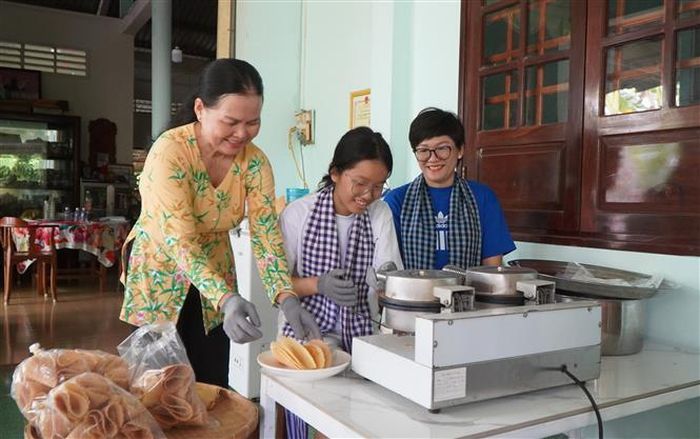 Du khách trải nghiệm làm bánh kẹp xoài. Ảnh: Nhựt An - TTXVN
