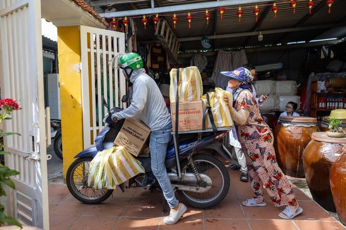 Do nằm trong khu vực đường hẻm nhỏ, những sản phẩm nước mắm Nam Ô được đưa đến tay người tiêu dùng bằng xe gắn máy. Ảnh: Xuân Quý - TTXVN