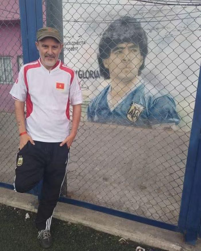 Andrés Carlos Sciapichetti mặc áo thể thao có quốc kỳ Việt Nam. đứng bên bức tranh tường vẽ danh thủ Maradona. Ảnh nhân vật cung cấp.