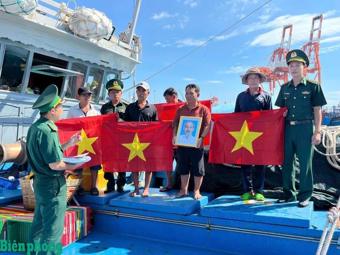 Tại cảng cá Quy Nhơn, tỉnh Gia Lai, Đồn Biên phòng cửa khẩu cảng Quy Nhơn, Bộ đội Biên phòng tỉnh Gia Lai tổ chức tuyên truyền các quy định về chống khai thác hải sản bất hợp pháp, không báo cáo và không theo quy định (IUU) cùng các nội dung liên quan đến Luật biển Việt Nam cho các chủ phương tiện, ngư dân, chủ tàu, thuyền trưởng, thuyền viên đi biển đánh bắt xa bờ. Trong ảnh: Cán bộ Đồn Biên phòng cửa khẩu cảng Quy Nhơn tặng cờ Tổ quốc và ảnh Bác Hồ cho ngư dân. Ảnh: Công Cường