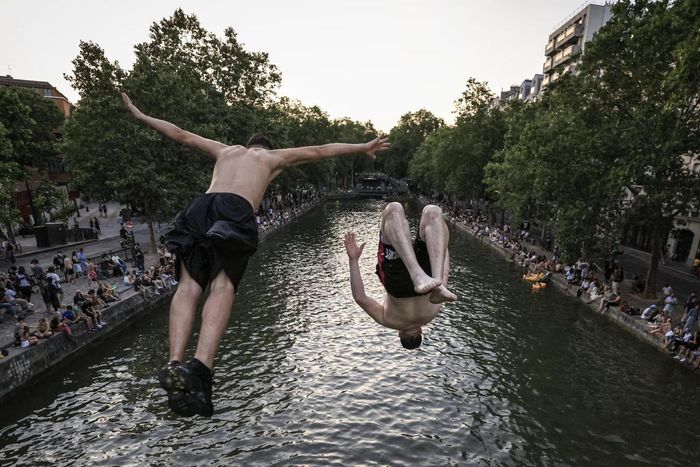 Người trẻ nhảy từ cầu xuống kênh Saint-Martin ở Paris (Pháp) để giải nhiệt.