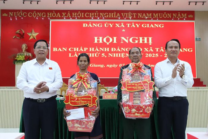 Phó Bí thư Thường trực Thành ủy Nguyễn Đình Vĩnh (bìa phải) và Bí thư Đảng ủy, Chủ tịch HĐND xã Tây Giang Bhling Mia (bìa trái) tặng quà cho hộ chính sách tại hội nghị. Ảnh: TRỌNG HUY