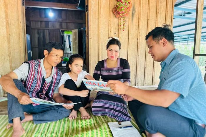 Anh Đinh Văn Ưm (bìa phải), Bí thư Chi bộ thôn An Hưng, xã An Lão trao đổi với người dân về các mô hình phòng, chống tảo hôn đăng trên báo Gia Lai. Ảnh: D.Đ